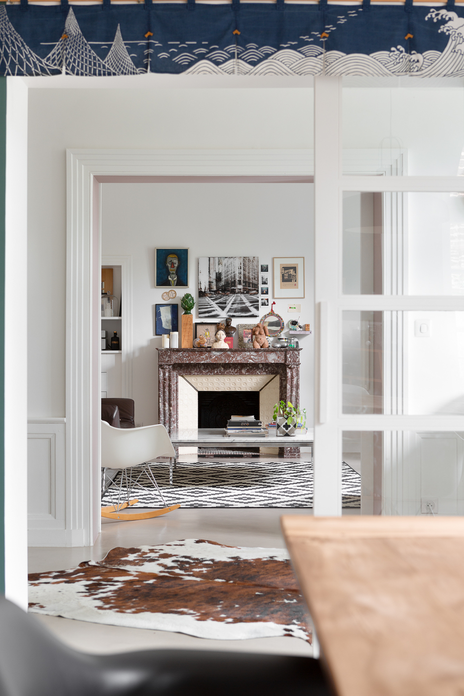 Hôtel particulier Rennes : salon aménagé autour de la cheminée en marbe, table basse en marbre, canapé et méridienne en cuir, béton ciré Marius Aurenti couleur "Mastic" en sol, tapis "peau de bête" dans le hall d'entrée